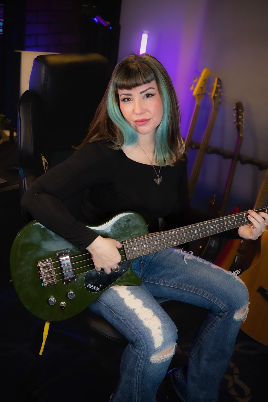 Leah seated with a guitar in a purple-lit recording studio